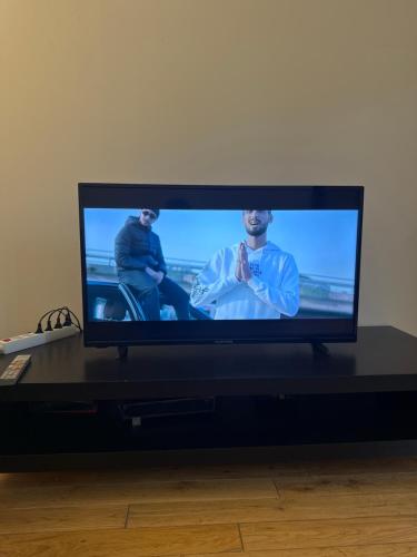 une télévision à écran plat assise sur une table noire dans l'établissement Stationnement Gratuit, 3mn du Métro, Parfait pour Télétravailler, à Maisons-Alfort