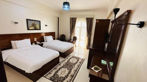 um quarto de hotel com duas camas e uma televisão em Badr Hotel & Resort El Kharga em Al Khārijah