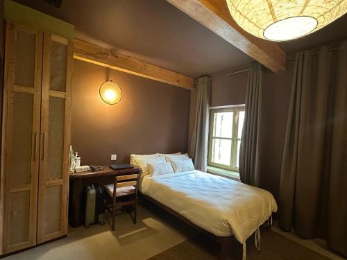 a bedroom with a bed and a desk and a window at The Melo pomelo courtyard. ( Right in between Thamel and basantapur durbar square) in Kathmandu