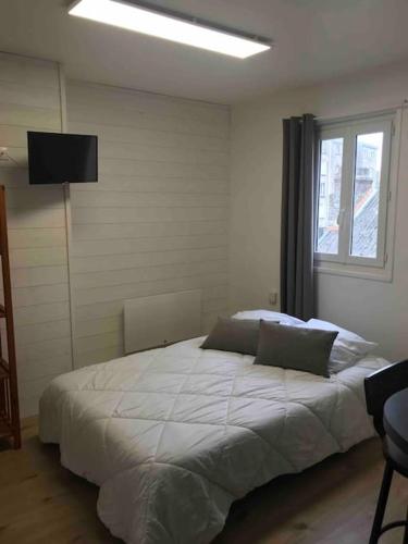 une chambre avec un grand lit blanc avec une fenêtre dans l'établissement Studio cosy au centre de Boulogne/Mer avec wifi, à Boulogne-sur-Mer
