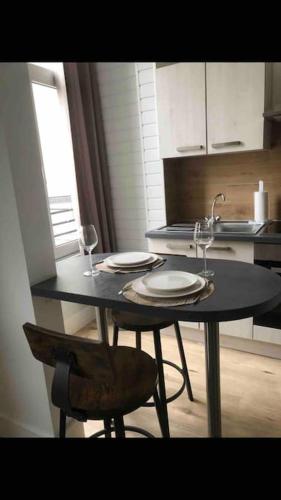 - une cuisine avec une table avec deux assiettes et des verres à vin dans l'établissement Studio cosy au centre de Boulogne/Mer avec wifi, à Boulogne-sur-Mer