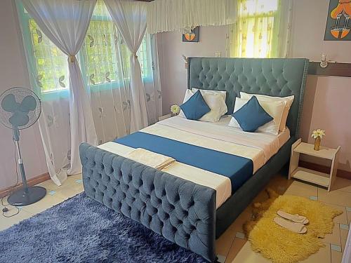 um quarto com uma cama grande e uma cabeceira azul em Homely apartments 4 em Kisumu