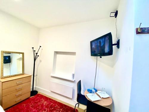 um quarto com uma mesa e uma televisão na parede em Lovely Cosy Studio Apartment Ground Floor In Central London em Londres