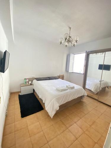 1 dormitorio con cama blanca y espejo en Habitacion Vacacional en piso compartido, en Castellón de la Plana