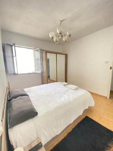 ein Schlafzimmer mit einem großen weißen Bett und einem Kronleuchter in der Unterkunft Habitacion Vacacional en piso compartido in Castellón de la Plana