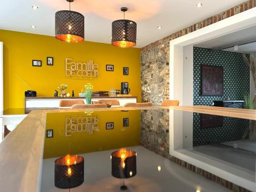 uma cozinha com paredes amarelas e um balcão com luzes em L'attente détente à 200 m du parc " Pairi Daiza " em Brugelette