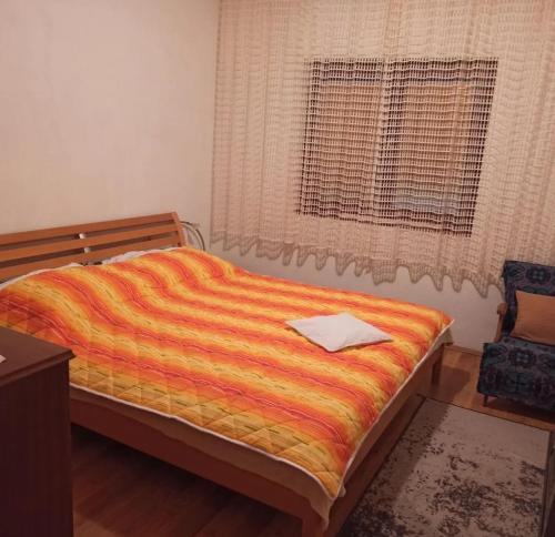 una camera da letto con un letto con una coperta arancione e una finestra di Drinska lepota a Ljubovija