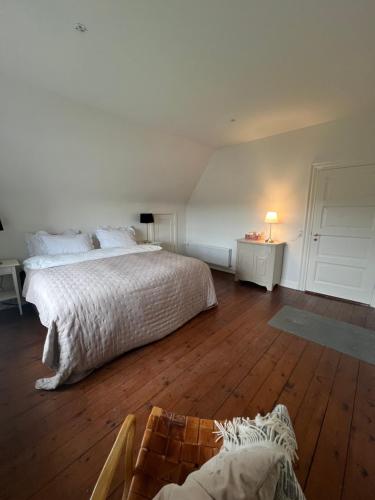 a white bedroom with a bed and a wooden floor at Sundsgården B&B in Ringe