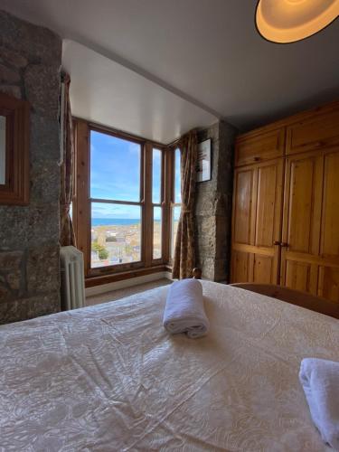 a bedroom with a large bed with a large window at HUER'S WATCH a beautifully presented PRIVATE APARTMENT with far reaching VIEWS Over ST IVES HARBOUR and BAY and FREE ONSITE PARKING for LARGER GROUPS book along with our Connecting TWO SISTER APARTMENTS in St Ives