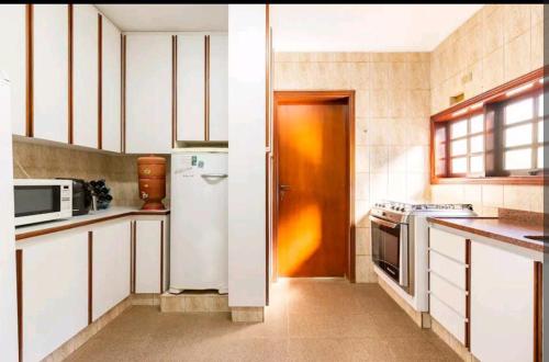 W kuchni znajduje się biała lodówka i kuchenka mikrofalowa. w obiekcie Casa em Cotia w mieście Cotia