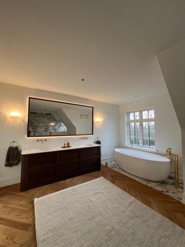 a large bathroom with a tub and a large mirror at Sundsgården B&B in Ringe
