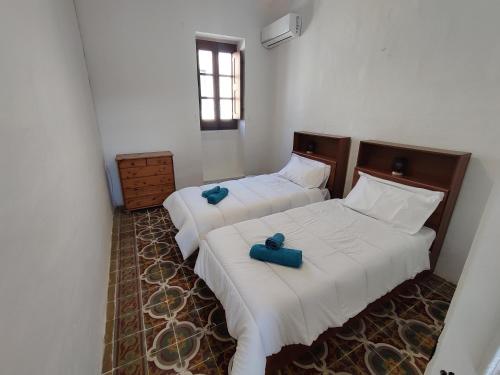 two beds in a room with two blue candles on them at Peaceful Traditional Maltese Townhouse in Luqa