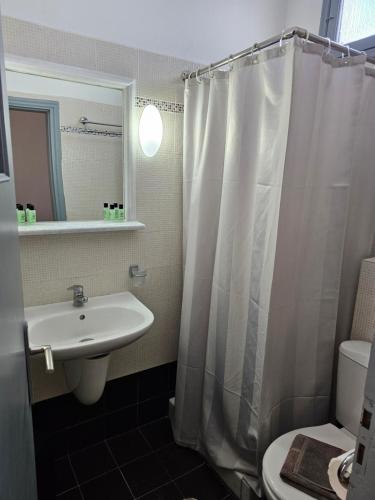 a bathroom with a sink and a shower curtain at Hotel Leta in Fira