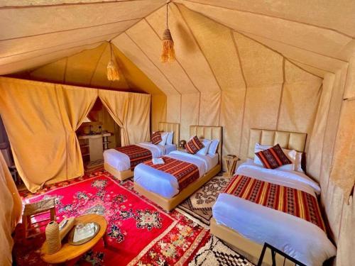 a group of four beds in a tent at Merzouga dreams Camp in Erfoud