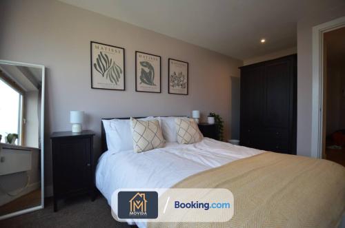 um quarto com uma cama branca com três fotografias na parede em One Bed Docklands By Movida Property Group Short Lets & Serviced Accommodation Hunslet em Hunslet