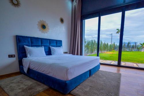 um quarto com uma cama azul e uma grande janela em Villa moderne Marrakech em Marrakech