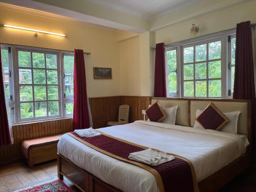 a bedroom with a large bed with red curtains at Ifseen Villa in Pelling