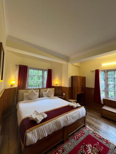 a bedroom with a large bed with red curtains at Ifseen Villa in Pelling