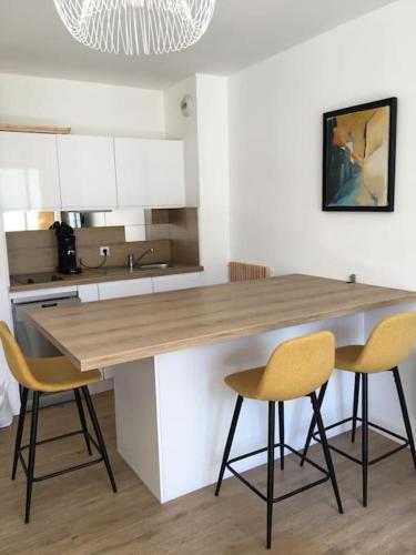- une cuisine avec un comptoir en bois et 2 chaises dans l'établissement Appartement lumineux proche du port et de la plage, au Pouliguen