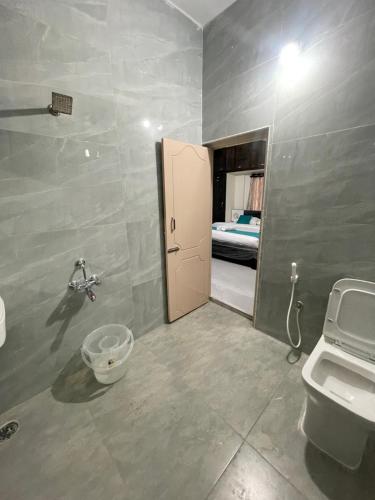 a bathroom with a toilet and a door with a bed at Sun Home Stays in Tirupati