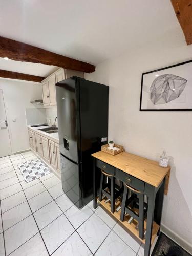 Il comprend une cuisine équipée d'un réfrigérateur noir et d'une table. dans l'établissement Superbe appartement neuf et cosy en centre ville, à Hyères