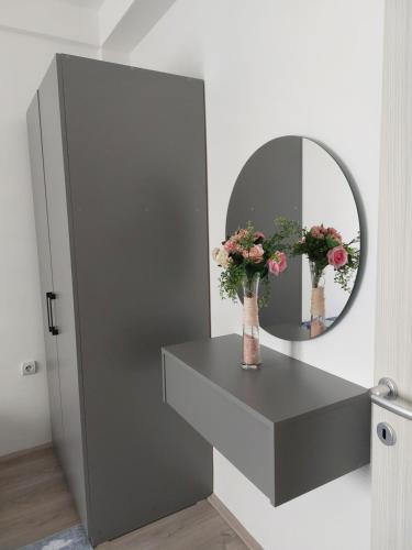 a bathroom with a mirror and flowers on a counter at Lili`s Apartment in Kumanovo