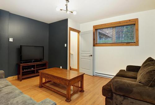 a living room with a couch and a tv at Chalet 9006 Chemin des Alpages by Les Chalets Alpins in Stoneham