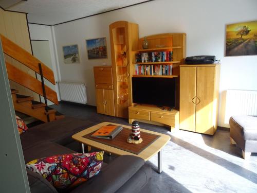 ein Wohnzimmer mit einem Sofa und einem TV in der Unterkunft Am Deichtor in Dornumersiel