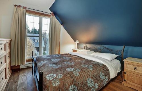 a bedroom with a bed and a blue wall at Chalet 9006 Chemin des Alpages by Les Chalets Alpins in Stoneham