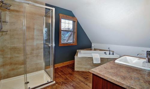 a bathroom with a shower and a sink and a tub at Chalet 9006 Chemin des Alpages by Les Chalets Alpins in Stoneham