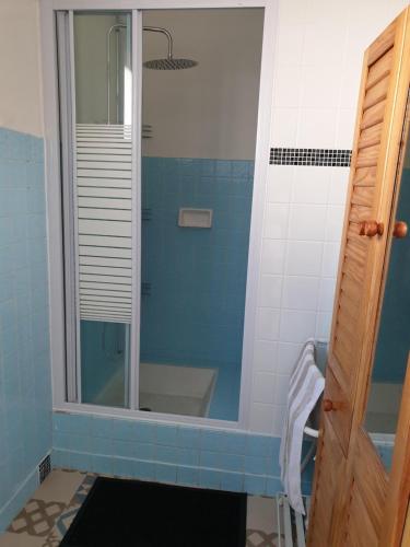 La salle de bains est pourvue d'une douche en verre avec du carrelage bleu. dans l'établissement Spacieux Appartement RDC tout confort, à Lorient