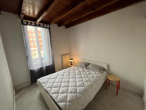 een slaapkamer met een wit bed en een raam bij Joli T3 duplex Compans Cafarelli in Toulouse