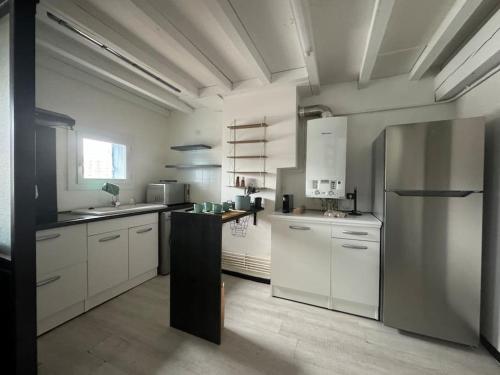 une cuisine avec des armoires blanches et un réfrigérateur en acier inoxydable dans l'établissement Joli T3 duplex Compans Cafarelli, à Toulouse