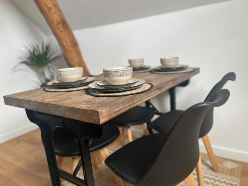 a wooden table with four chairs and cups on it at Appartement Aéroport Orly in Athis-Mons