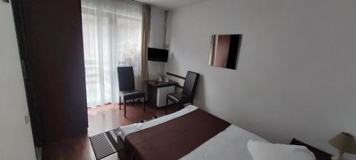 a room with a bed and a desk and a window at CASA RYANA SINAIA in Sinaia