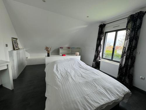 um quarto branco com uma cama e uma janela em Villa Benouville em Bénouville