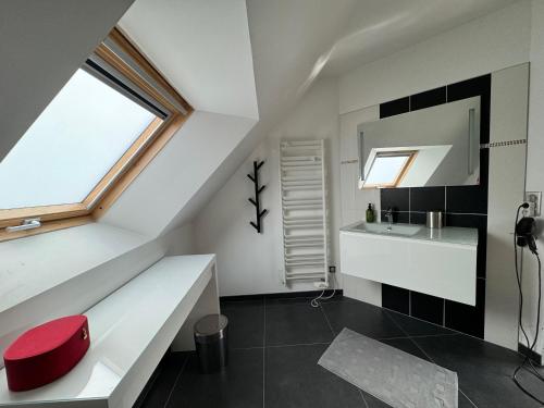 La salle de bains est pourvue d'un lavabo blanc et d'un tabouret rouge. dans l'établissement Villa Benouville, à Bénouville