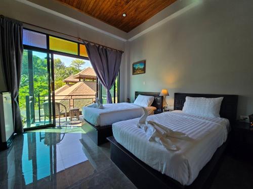 two beds in a room with a view of a balcony at Baan Koh Kwang Pool Villa Krabi in Krabi town