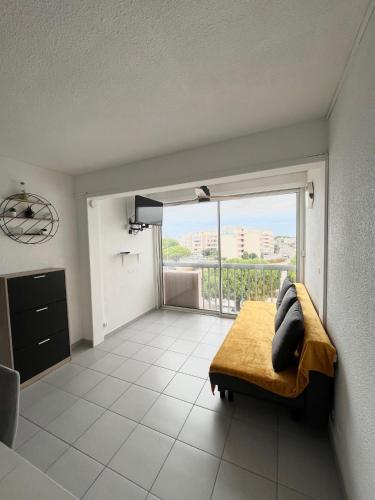 un salon avec un canapé et une grande fenêtre dans l'établissement Appartement devant la mer + parking, au Grau-du-Roi