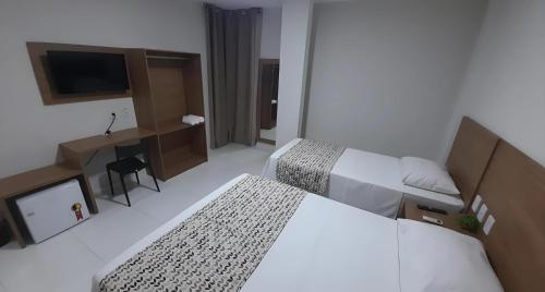 a hotel room with two beds and a television at NOVO HOTEL in Conceição do Coité