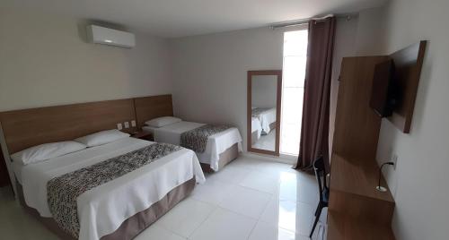 a hotel room with two beds and a television at NOVO HOTEL in Conceição do Coité