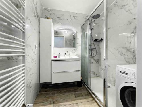 une salle de bain blanche avec un lavabo et une douche dans l'établissement 1 min to beach with parking 3 bedroom flat (2 AC), à Nice