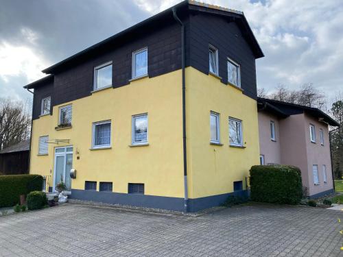 uma casa amarela e preta com um telhado preto em Ferienwohnungen Pohl em Bad Rodach