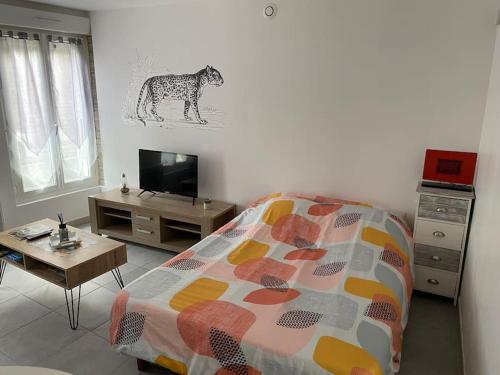 1 dormitorio con cama, mesa y TV en Studio en rez-de-chaussée avec cour dans le centre de Vendome, en Vendôme