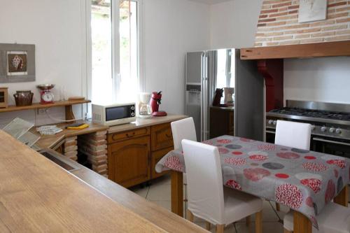 une cuisine avec une table et des chaises ainsi qu'une cuisine avec une table et une table dans l'établissement Maison familiale proche du lac, à Biscarrosse