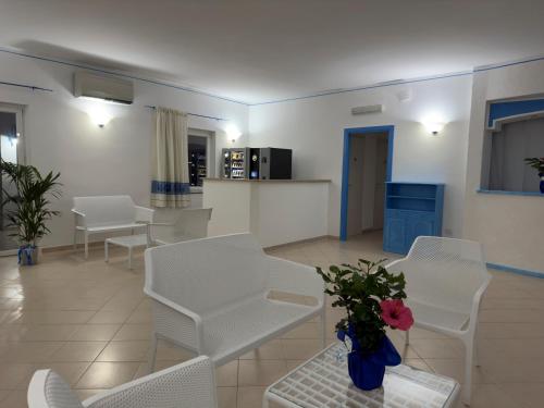 a living room with white chairs and a vase of flowers at Garden Hotel Alghero in Fertilia