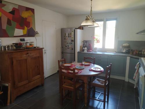 une cuisine avec une table, des chaises et un réfrigérateur dans l'établissement Maison en Provence, à Entraigues-sur-la-Sorgue