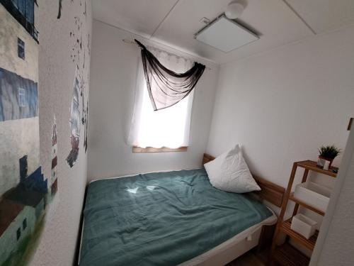 ein kleines Schlafzimmer mit einem grünen Bett und einem Fenster in der Unterkunft Ferienhaus am Edersee-scheid in Waldeck
