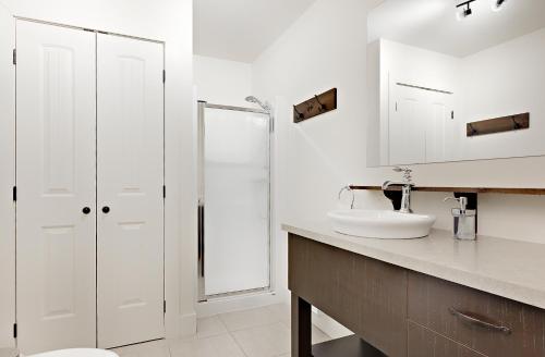 ein weißes Badezimmer mit einem Waschbecken und einem Spiegel in der Unterkunft 9009 chemin des Alpages in Stoneham