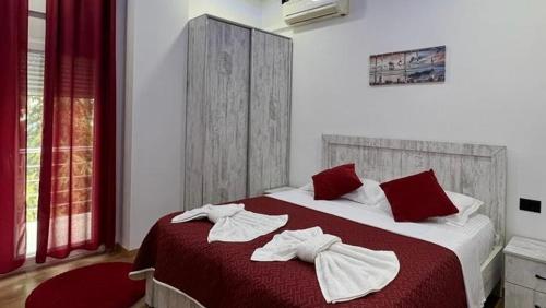 a bedroom with a red and white bed with towels on it at Lundra in Gramsh